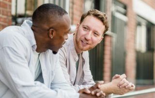 2 men leaning on railing having conversation