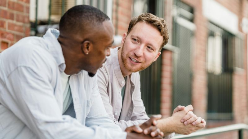 2 men leaning on railing having conversation
