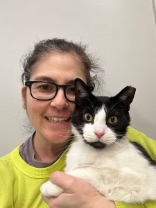 black and white cat held by woman wearing glasses